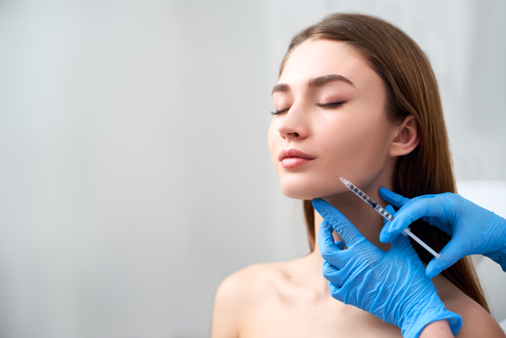 Woman smiling with eyes closed as injection specialist administers dermal fillers, Tuscaloosa, AL