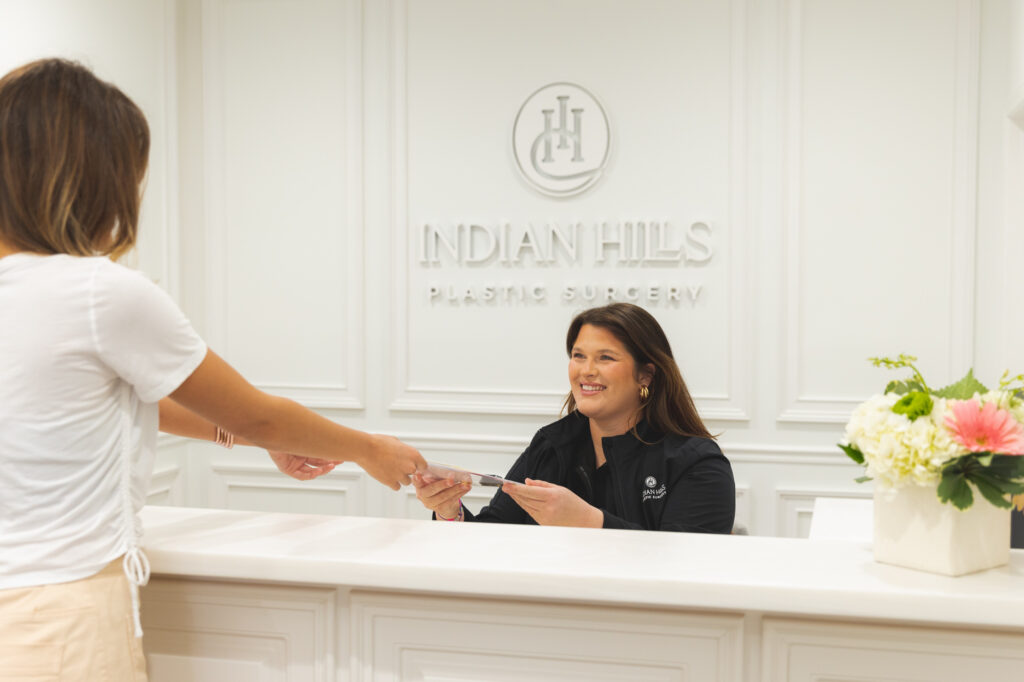 Patient Handing a Clipboard to a Front Desk Attendant at Indian Hills Aesthetics